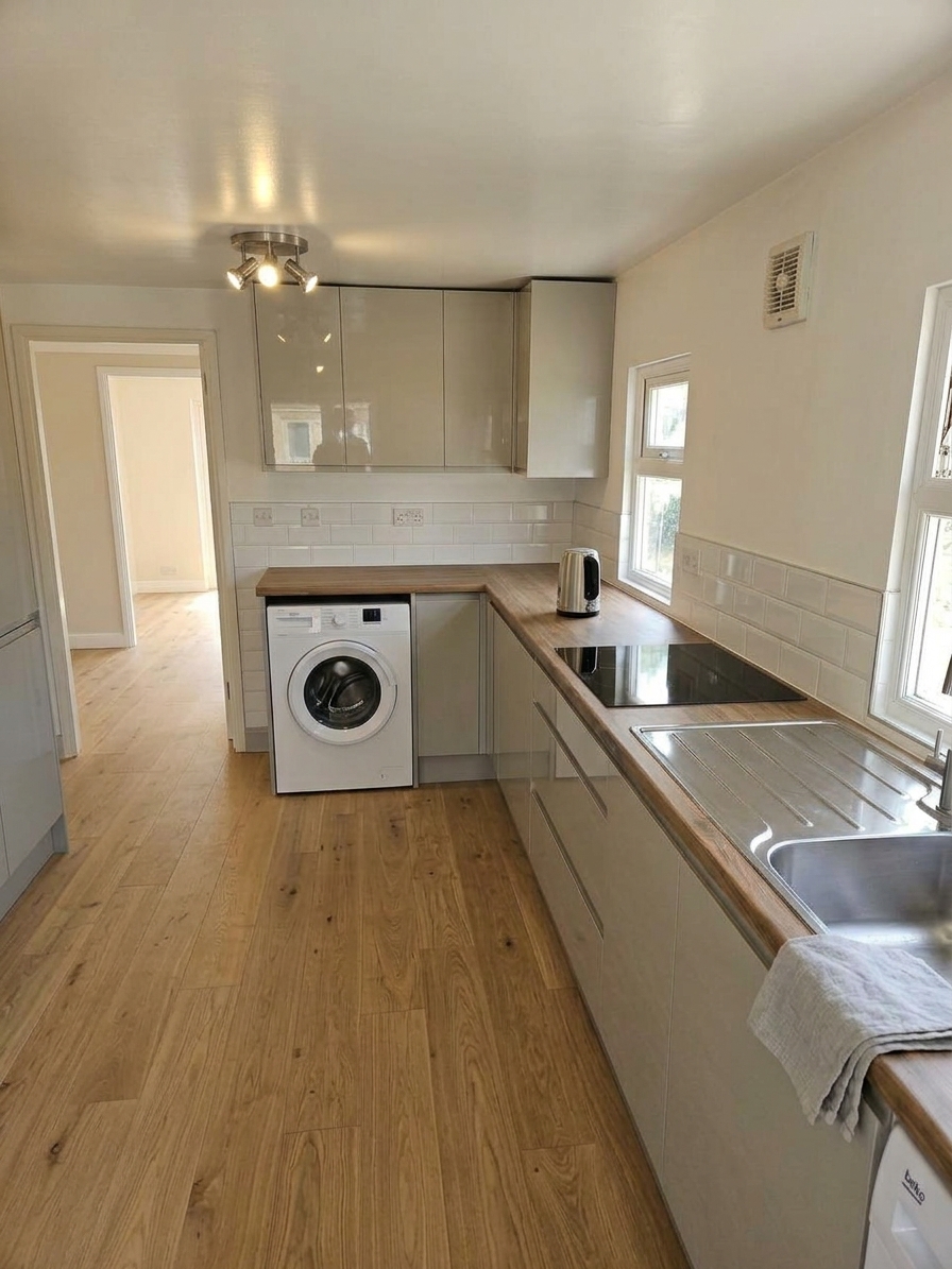 Kitchen with cashmere gloss cabinets, oak worktops and wooden flooring